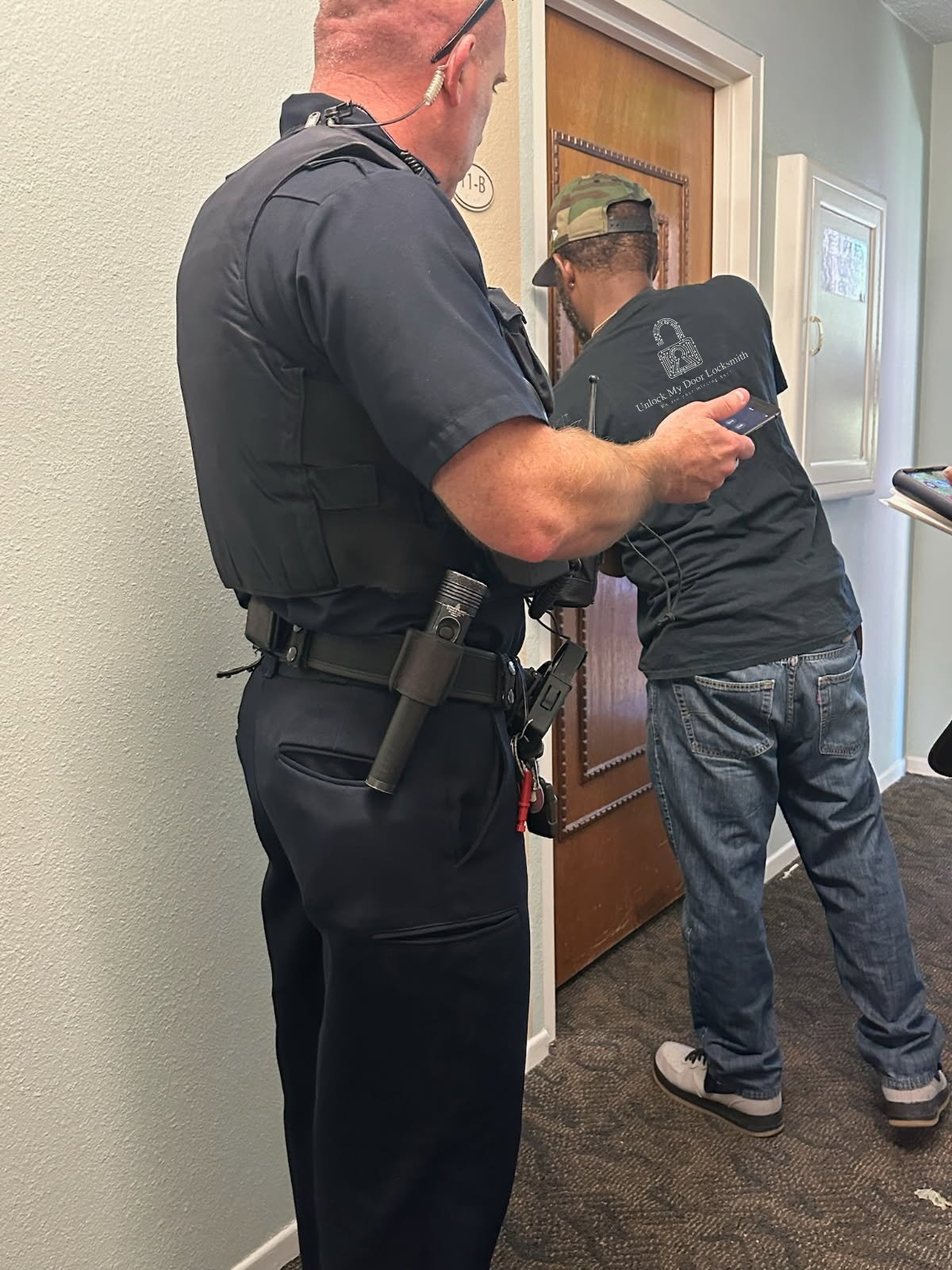 Show a secure commercial building entrance with a modern access control system. A locksmith is shown installing or maintaining the system. The scene should be clean, professional, and convey a sense of security and sophistication.