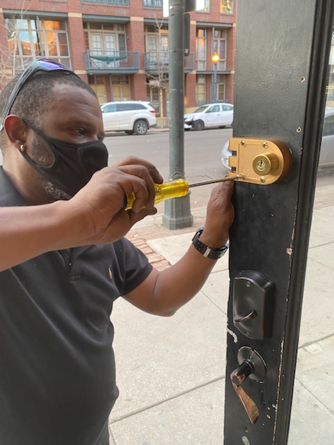 A new, gleaming high-security lock being installed on a sturdy wooden door. The scene conveys strength and reliability. The installation is performed with precision and care, ensuring optimal functionality and security.